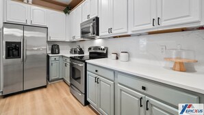 A modern kitchen with white cabinets, stainless steel appliances, and a marble countertop. - The Epic 12207 Vista Cay Resort Orlando Florida (Orlando)