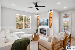Ein modernes Wohnzimmer mit Sofa, Hocker, Couchtisch aus Holz und Kamin.