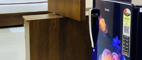 Una sala moderna con un mueble de entretenimiento de madera, un televisor de pantalla plana montado en él y un refrigerador con un diseño floral.