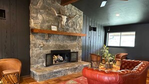 Un salon chaleureux avec une cheminée en pierre, un canapé en cuir et des éléments décoratifs en bois.
