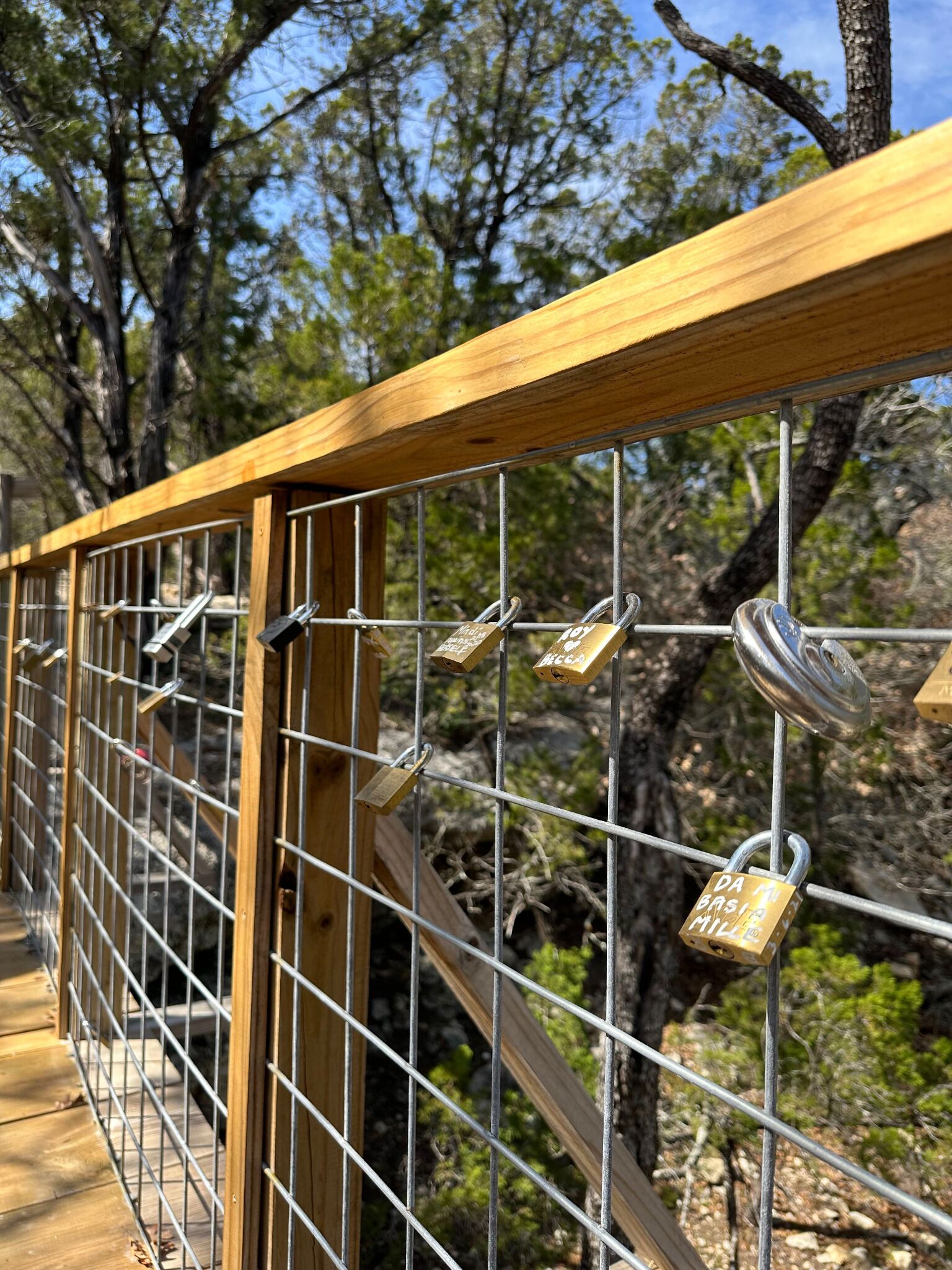 Un pont en bois doté de rampes métalliques et orné de nombreux cadenas.