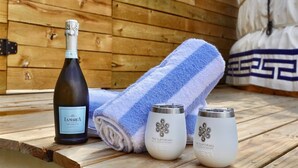 A wooden deck with a bottle of wine, a towel, and two glass containers.