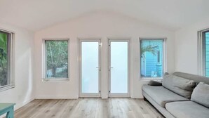 Ein Zimmer mit grauem Sofa, zwei Schiebeglasüren und Holzboden.