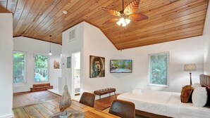Un'ampia stanza con soffitto in legno, un tavolo da pranzo, un divano e opere d'arte alle pareti.