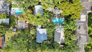 Vista aerea di una zona residenziale con diverse case, una piscina e vegetazione lussureggiante.