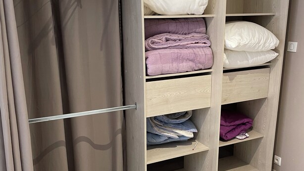 A walk-in closet with open shelves, a hanging rod, and a folded bed. - Getaway to Carmaux (Carmaux)