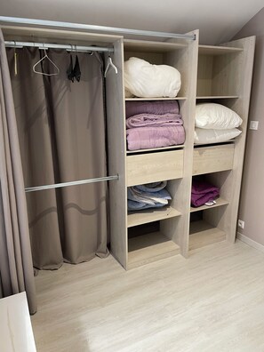 A walk-in closet with open shelves, a hanging rod, and a folded bed. - A Short Getaway in Carmaux (Carmaux)