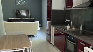A modern kitchen with a dining area, a TV, and a sofa. - Getaway to Carmaux (Carmaux)