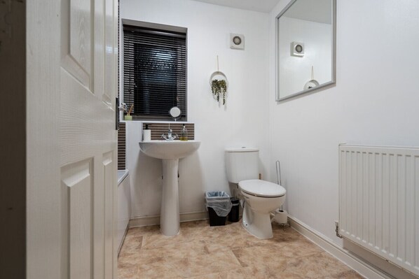 A bathroom with a white sink, toilet, and radiator.