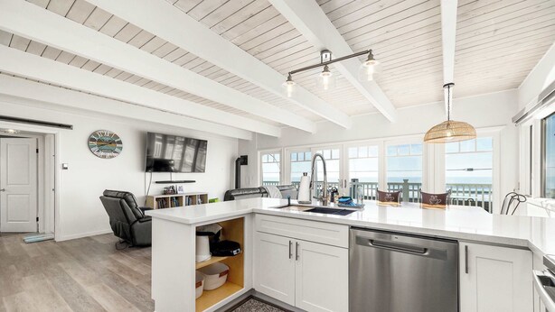 Een moderne keuken met witte kasten, een roestvrijstalen vaatwasser en een groot eiland met een spoelbak.