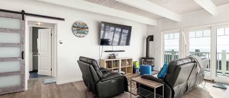 A living room with a sofa, a recliner, a TV, and a bookshelf.
