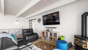 Een woonkamer met een bank, een televisie, een boekenkast en een open haard.