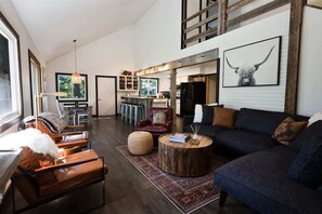 Un salón espacioso con un sofá grande, una mesa de centro y una zona de comedor con barra.