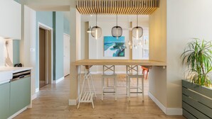 A modern kitchen with a wooden island, pendant lights, and a painting on the wall. - Infinity & Beyond Seafront Apartments by Halu! (Thessaloniki)