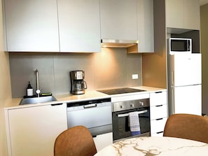 Eine moderne Küche mit integrierter Kaffeemaschine, Mikrowelle, Geschirrspüler und Backofen.
