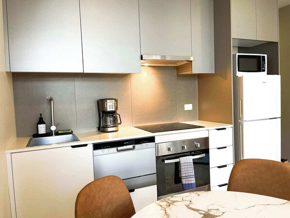 Una cocina moderna equipada con cafetera, microondas, lavavajillas y horno.