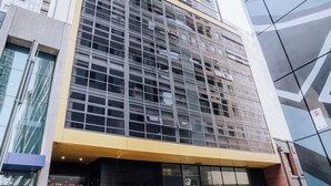 A modern building with a glass facade, a yellow awning, and a sign that reads 'METRO.' - Modern and Elegant 1BD Apartment in the CBD (Melbourne)