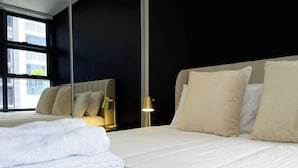 A neatly made bed with white linens, a folded white towel, and a beige textured area rug. - Modern and Elegant 1BD Apartment in the CBD (Melbourne)