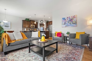 Uma sala de estar moderna com sofá, poltrona, mesa de centro e tapete.