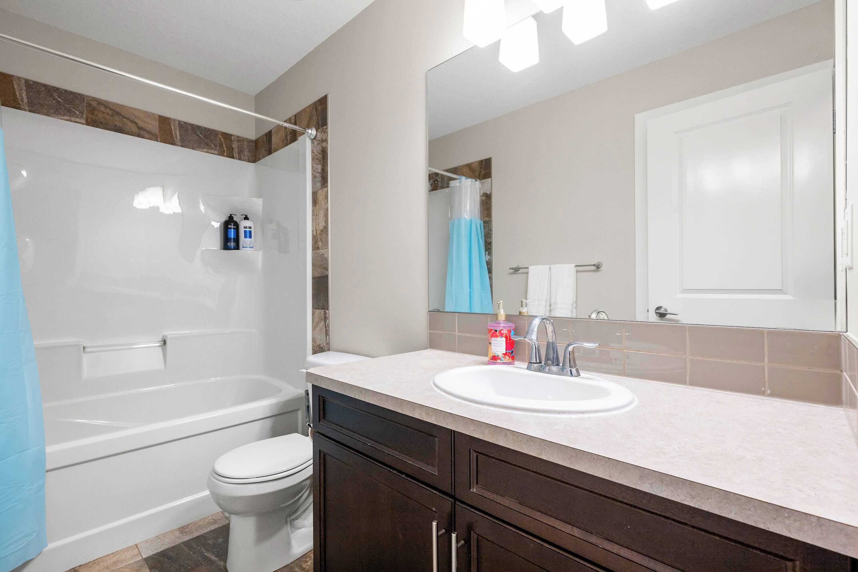 A bathroom with a bathtub, toilet, sink, and dark wooden cabinets.