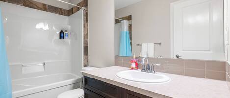 A bathroom with a bathtub, toilet, sink, and dark wooden cabinets.