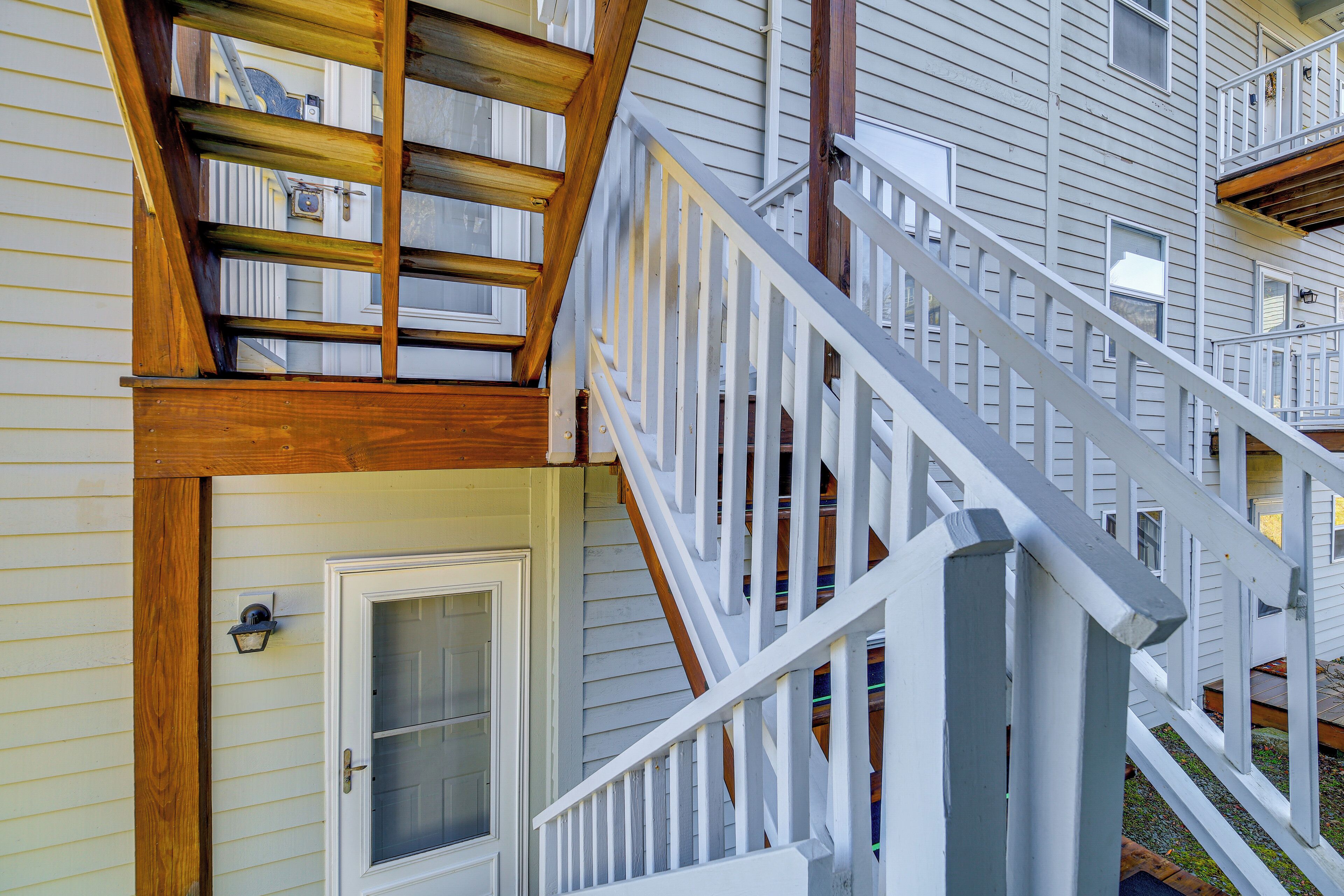 A wooden staircase with white railings leading to a second-floor balcony.