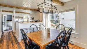 A spacious dining area with a wooden table and chairs, a chandelier, and a view of the outside.