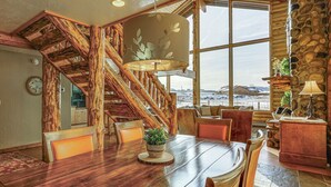 A spacious dining area with a wooden table, chairs, and a large window offering a view of the outdoors.