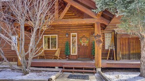 A log cabin with a porch, wooden steps, and a wreath on the door.
