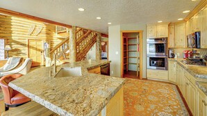 A spacious kitchen with granite countertops, wooden cabinets, and a built-in oven.