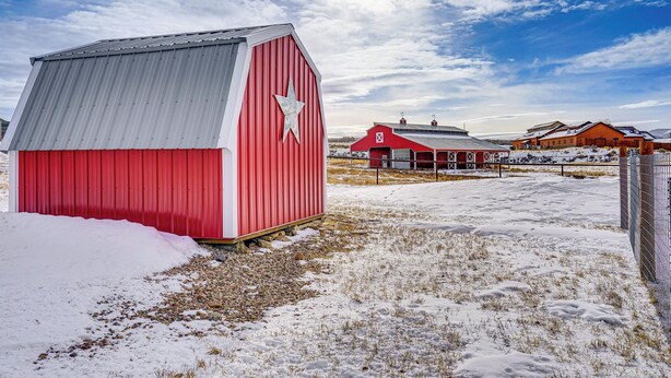A red barn with a white star on its side, surrounded by snow-covered ground and other buildings in the background. - 10 Mi to Deer Valley: Mtn-view Gem w/ Game Room (Park City)