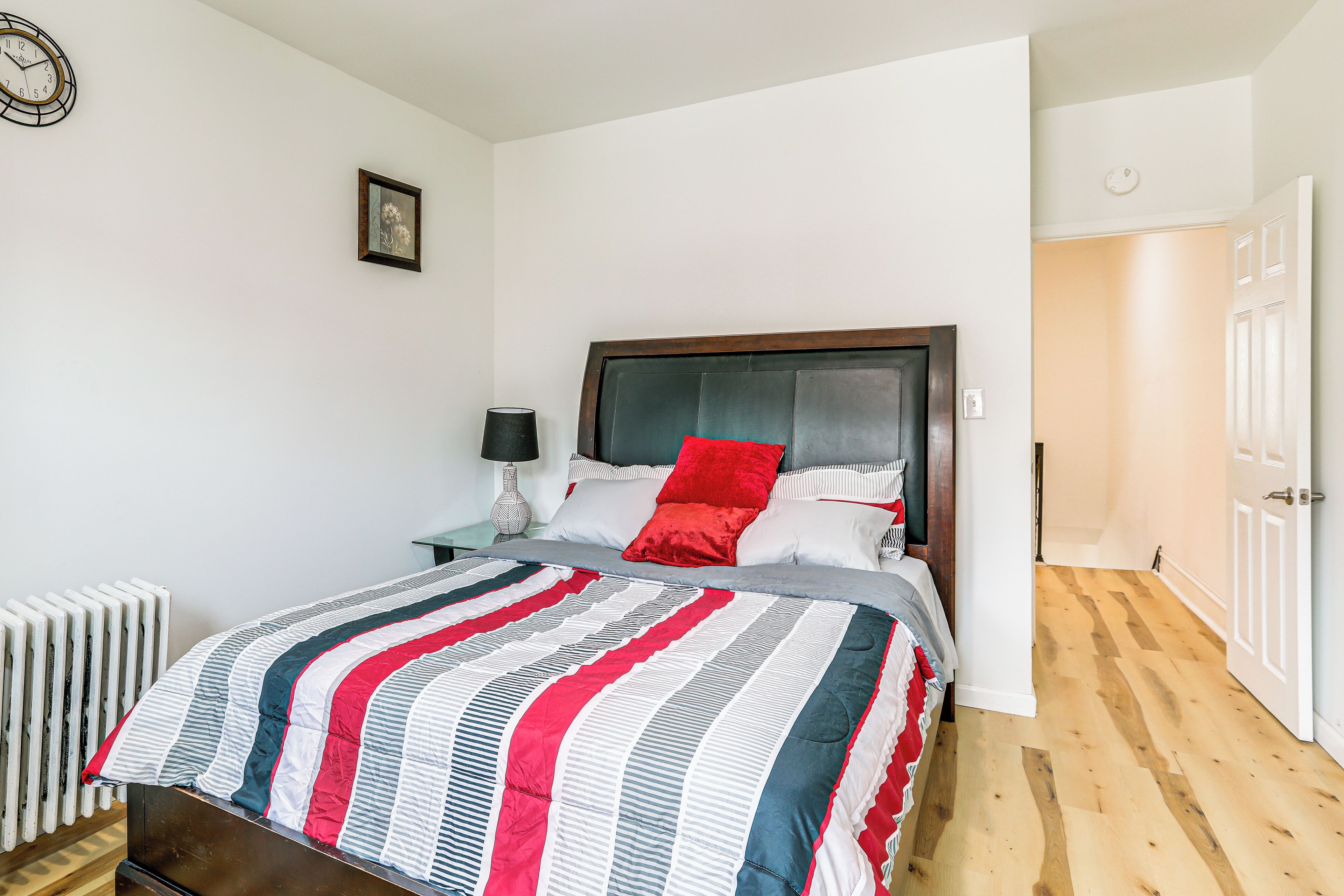 Une chambre à coucher avec un lit, une table de chevet, une lampe et un radiateur.