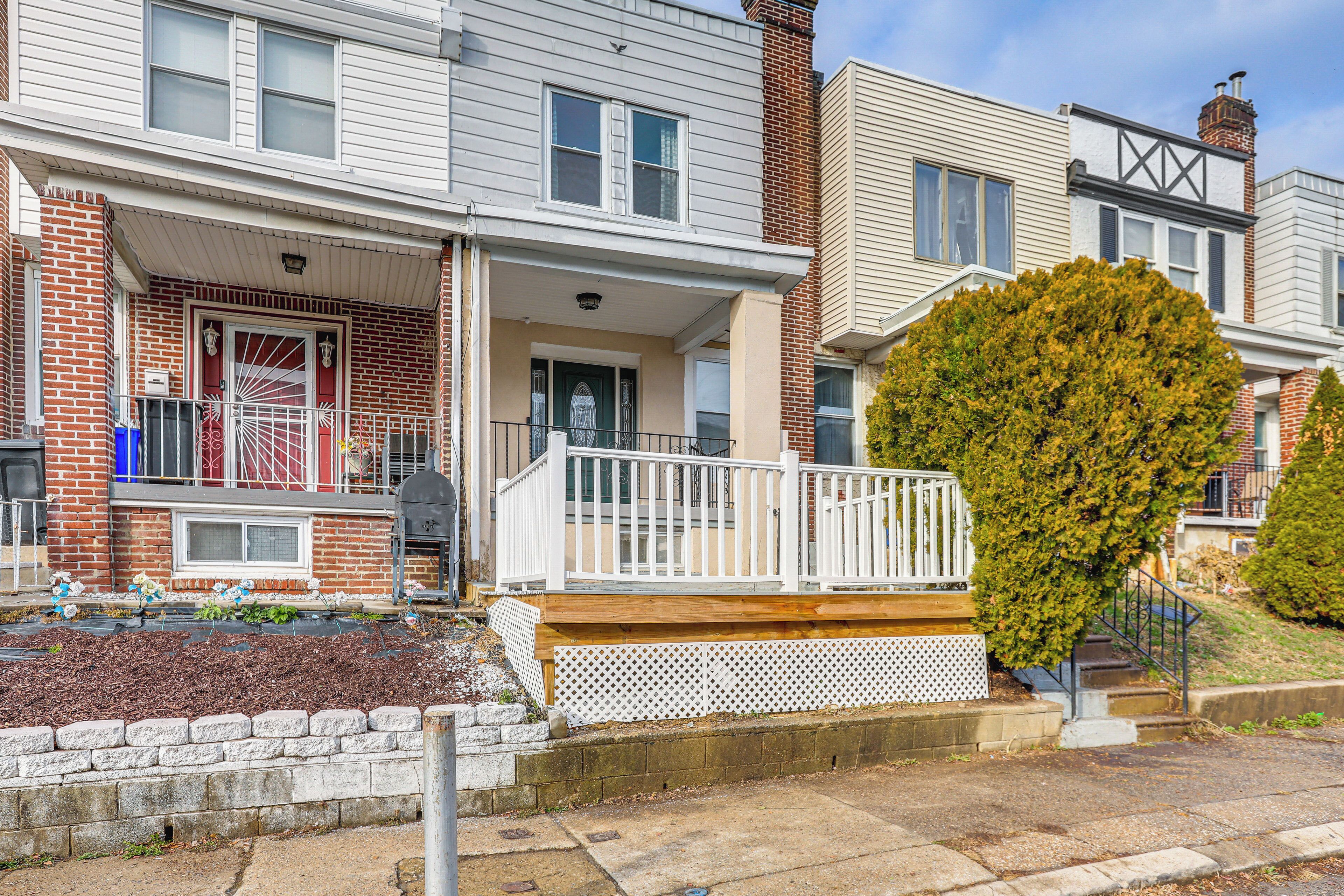 A two-story residential building with a front porch, a small deck, and a brick facade.