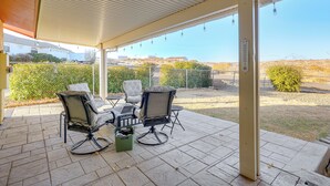 A covered patio with two chairs and a table, a trash bin, and a thermometer. - Bring Your Pup: Spring Valley Home w/ Fenced Yard! (Mayer)