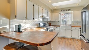 A kitchen with white cabinets, a wooden countertop, a coffee maker, and a sign that reads "BAKERY". - Bring Your Pup: Spring Valley Home w/ Fenced Yard! (Mayer)