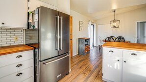 A kitchen with a stainless steel refrigerator, wooden countertops, white cabinets, and a dining area with a wooden table and chairs. - Bring Your Pup: Spring Valley Home w/ Fenced Yard! (Mayer)