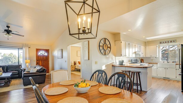 A spacious living room with a wooden dining table, a kitchen with a central island, and a separate dining area with a chandelier. - Bring Your Pup: Spring Valley Home w/ Fenced Yard! (Mayer)