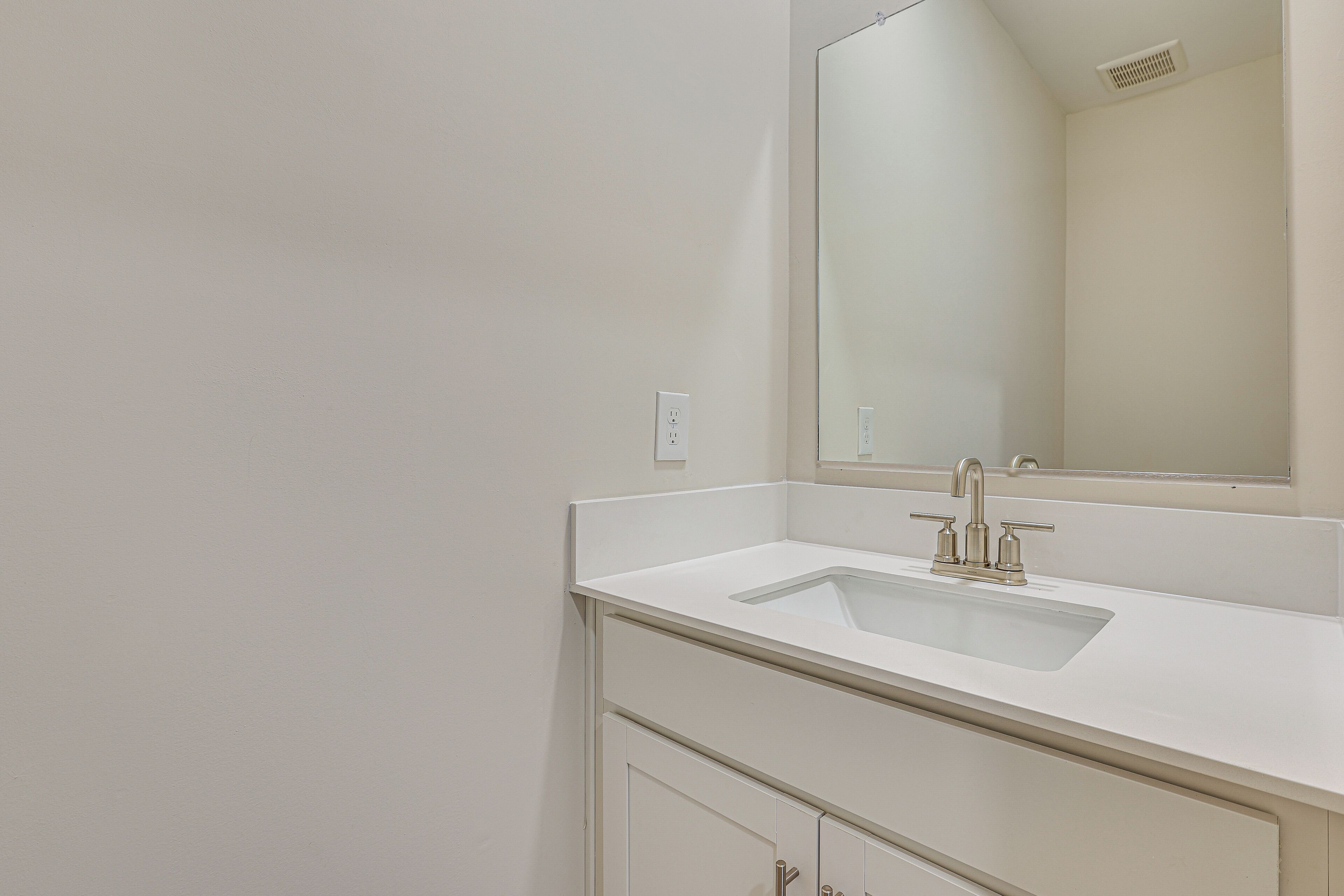 A bathroom with a white sink, a mirror, and a cabinet.