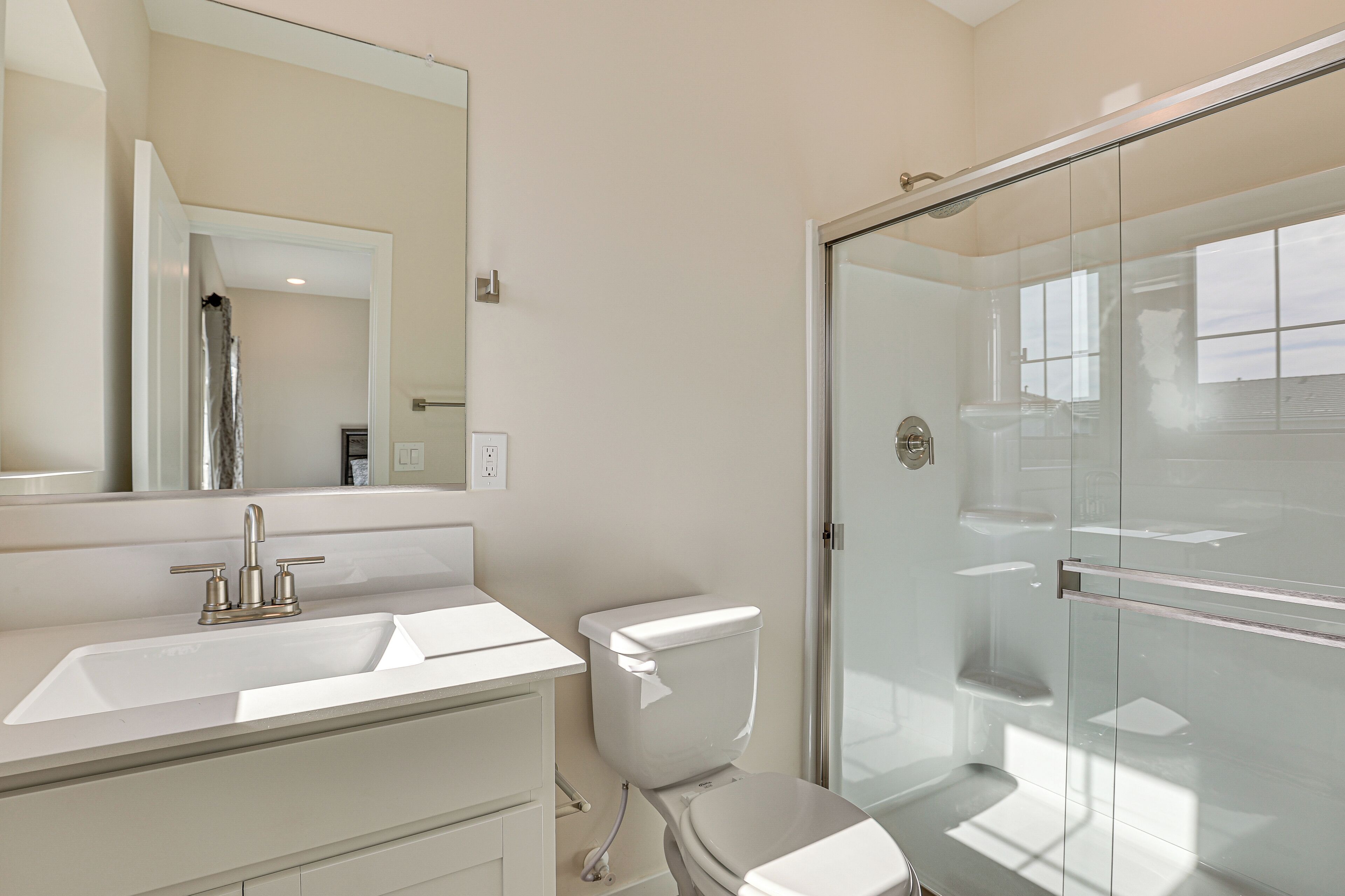 A modern bathroom with a glass shower enclosure, a white sink, and a toilet.