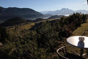 Una mesa con una silla en un paisaje montañoso con vistas a montañas distantes.