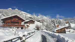 Un village de montagne enneigé, avec des bâtiments en bois et un ciel bleu azur.