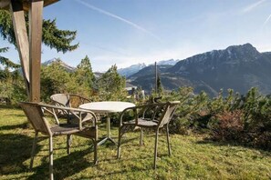 Un espacio de estar al aire libre con una mesa y sillas, con vistas a un paisaje montañoso.