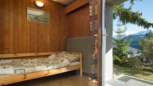 Une pièce en bois avec un lit, un tableau au mur et une vue sur les montagnes.