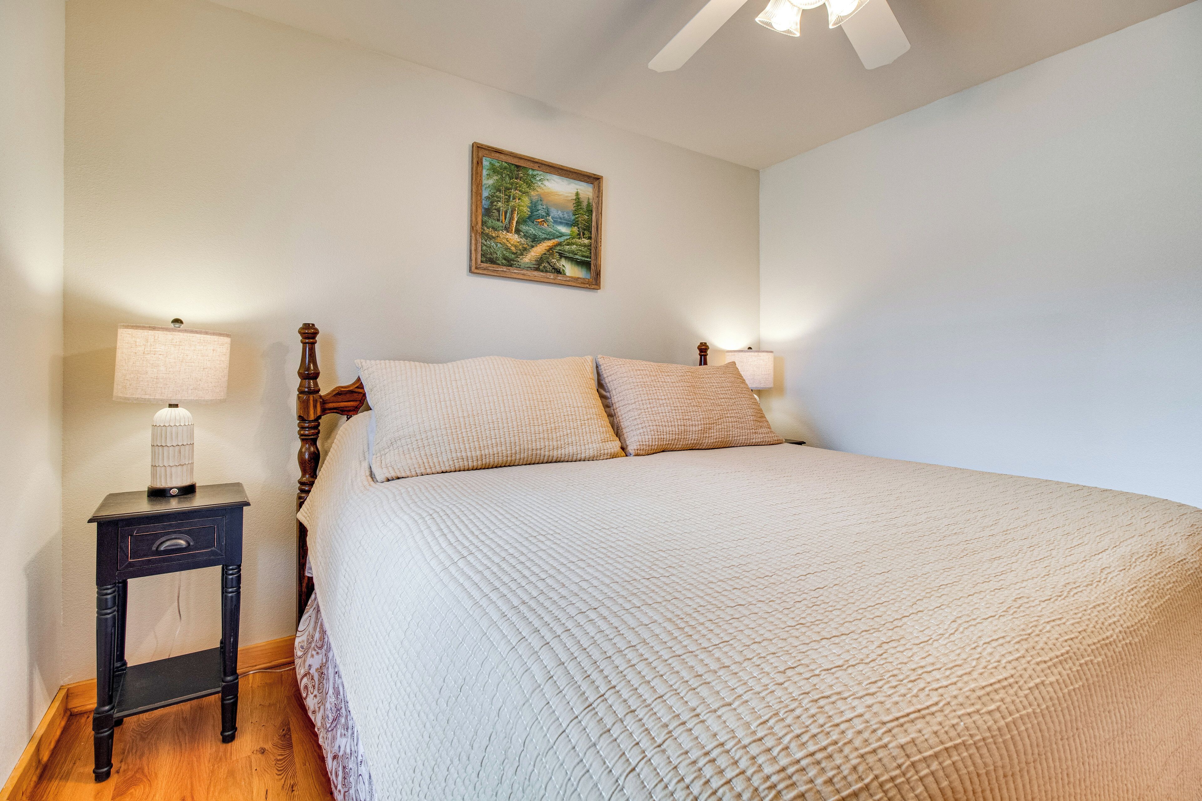 Une chambre à coucher avec un lit, une table de chevet, une lampe et un tableau au mur.