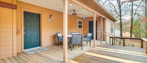 A wooden deck with a covered seating area, a door, and a welcome sign.