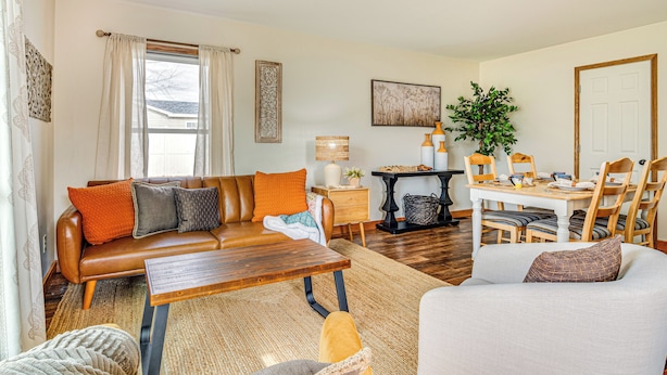 A living room with a brown leather sofa, a wooden coffee table, a white armchair, and a dining table with chairs. - 17 Mi to Brookville Lake: Home w/ In-unit Laundry (Connersville)