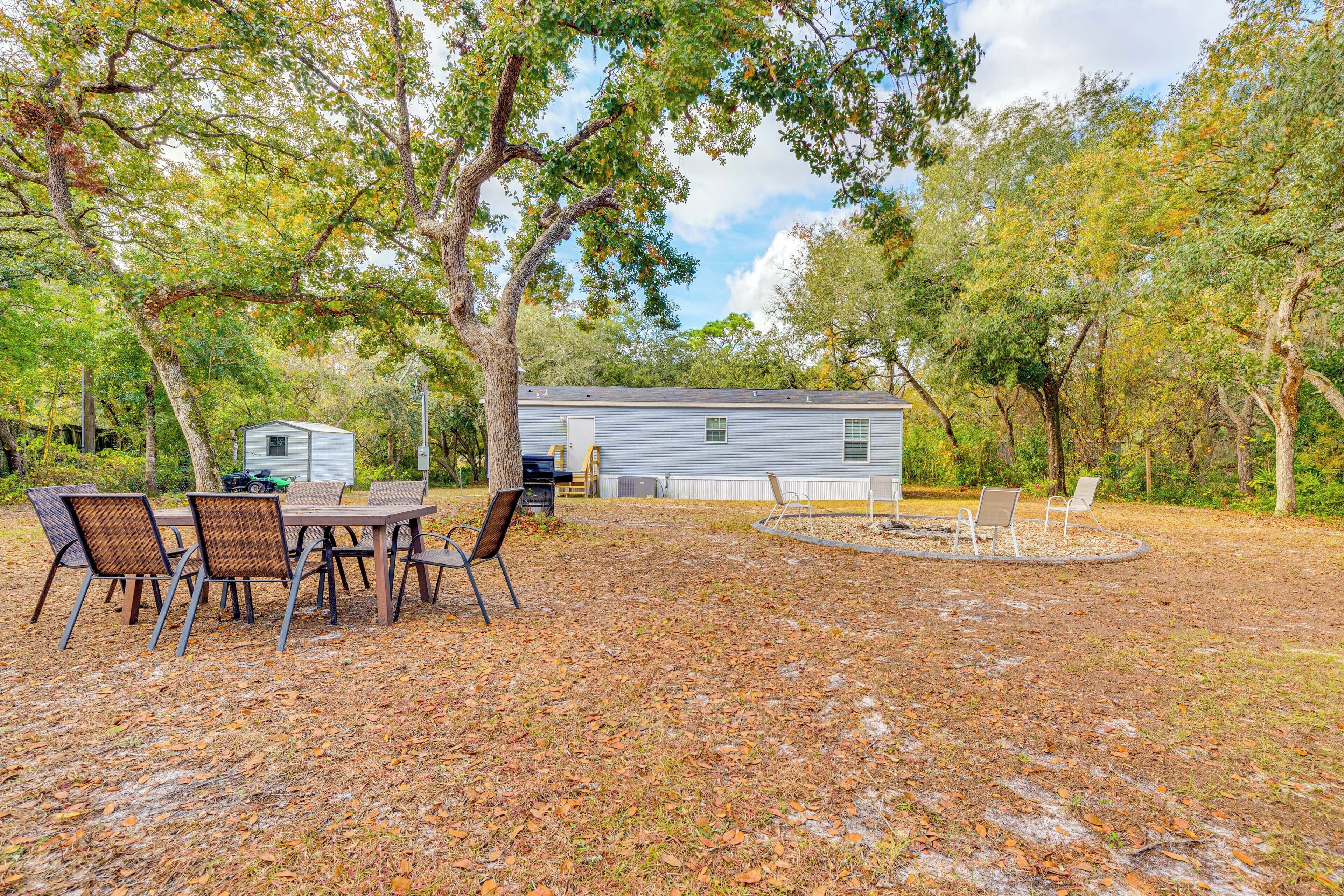 A backyard with a dining table and chairs, a small shed, and a house in the background.