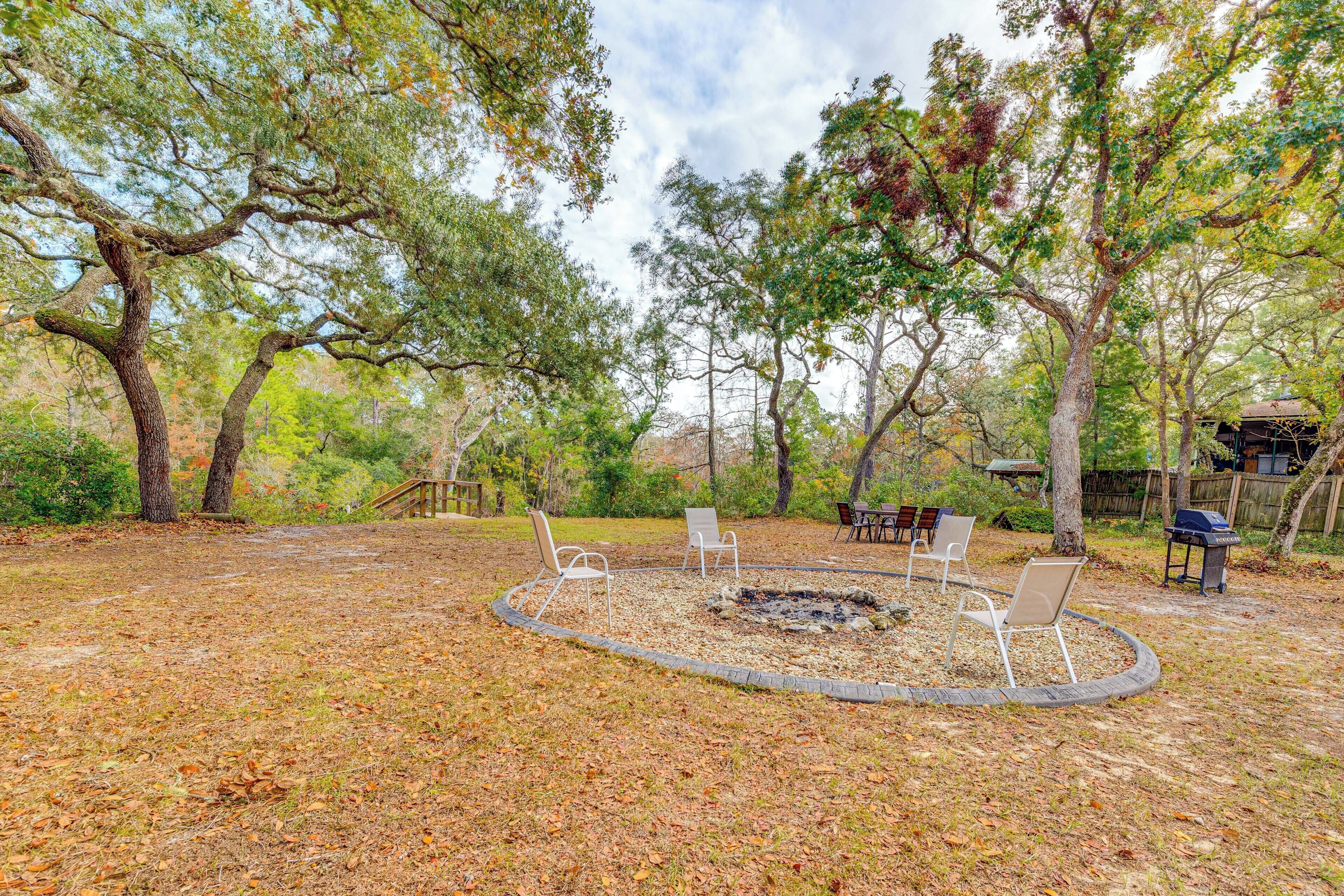 A circular seating area with fire pit, surrounded by trees and outdoor furniture.