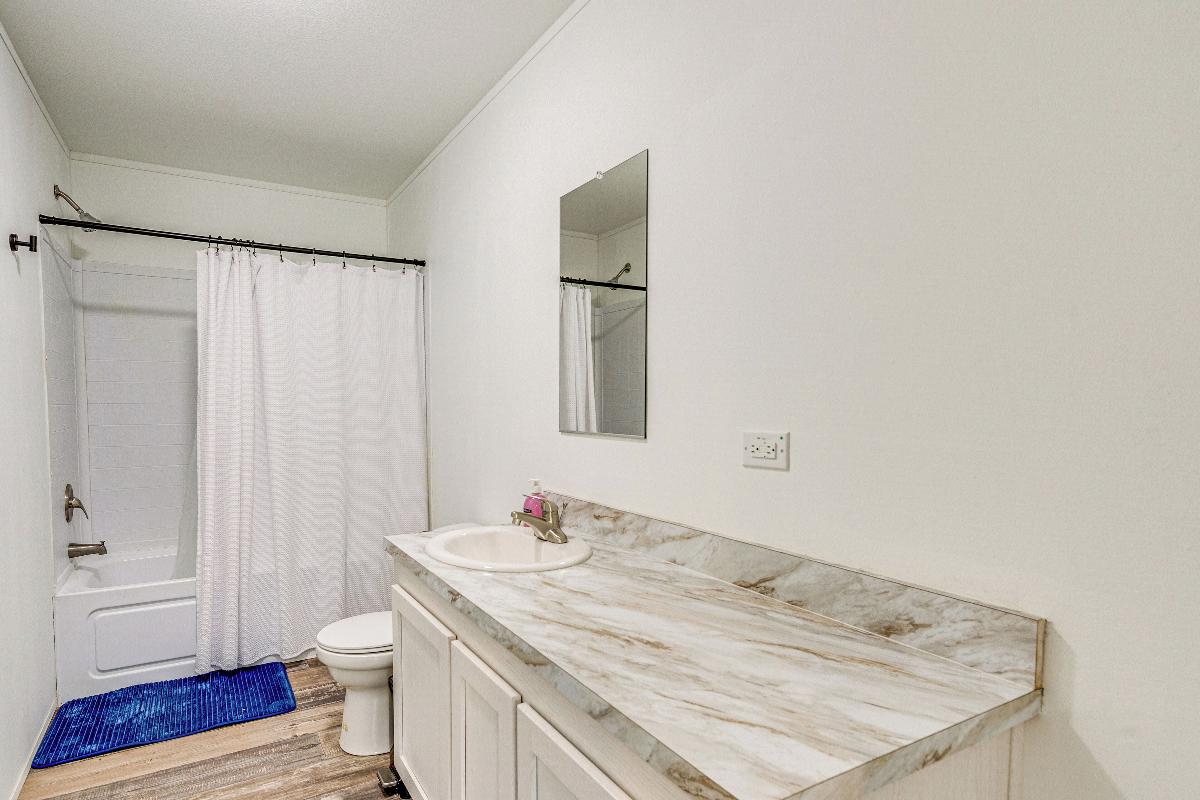 A bathroom with a bathtub, toilet, sink, and a mirror.