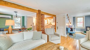 Een moderne woonkamer met een witte bank, een houten salontafel en een accentmuur van baksteen.